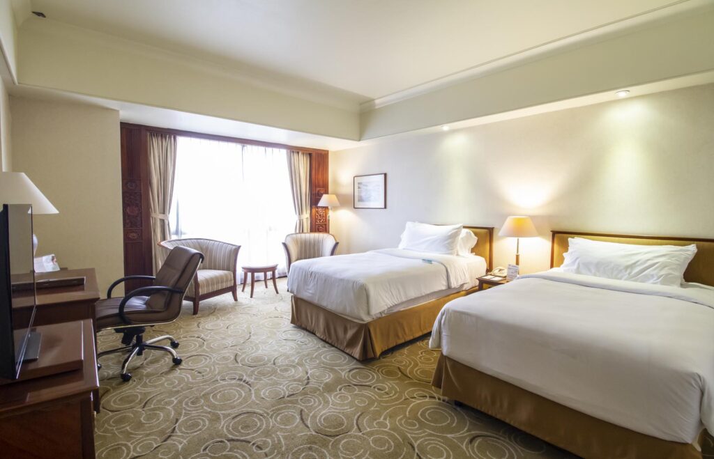 2 single beds and working desk in the grand deluxe room ath the sultan hotel