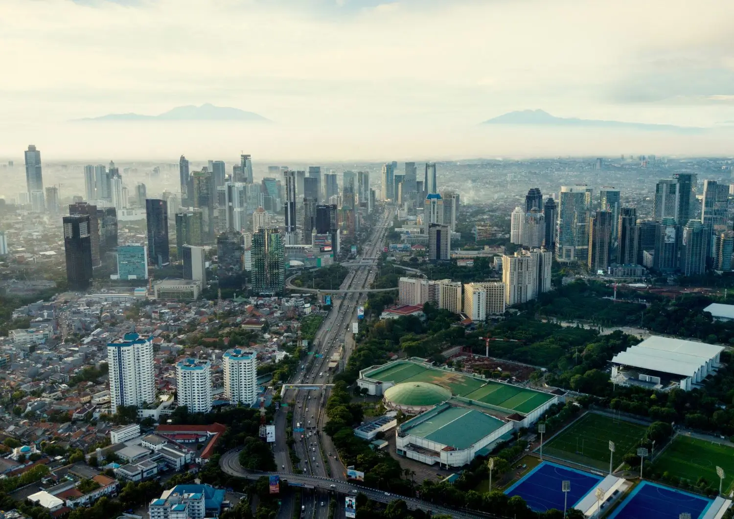 Pemandangan udara kota yang memamerkan gedung-gedung tinggi dan lanskap perkotaan area hotel dekat gbk senayan jakarta di bawah langit biru cerah.
